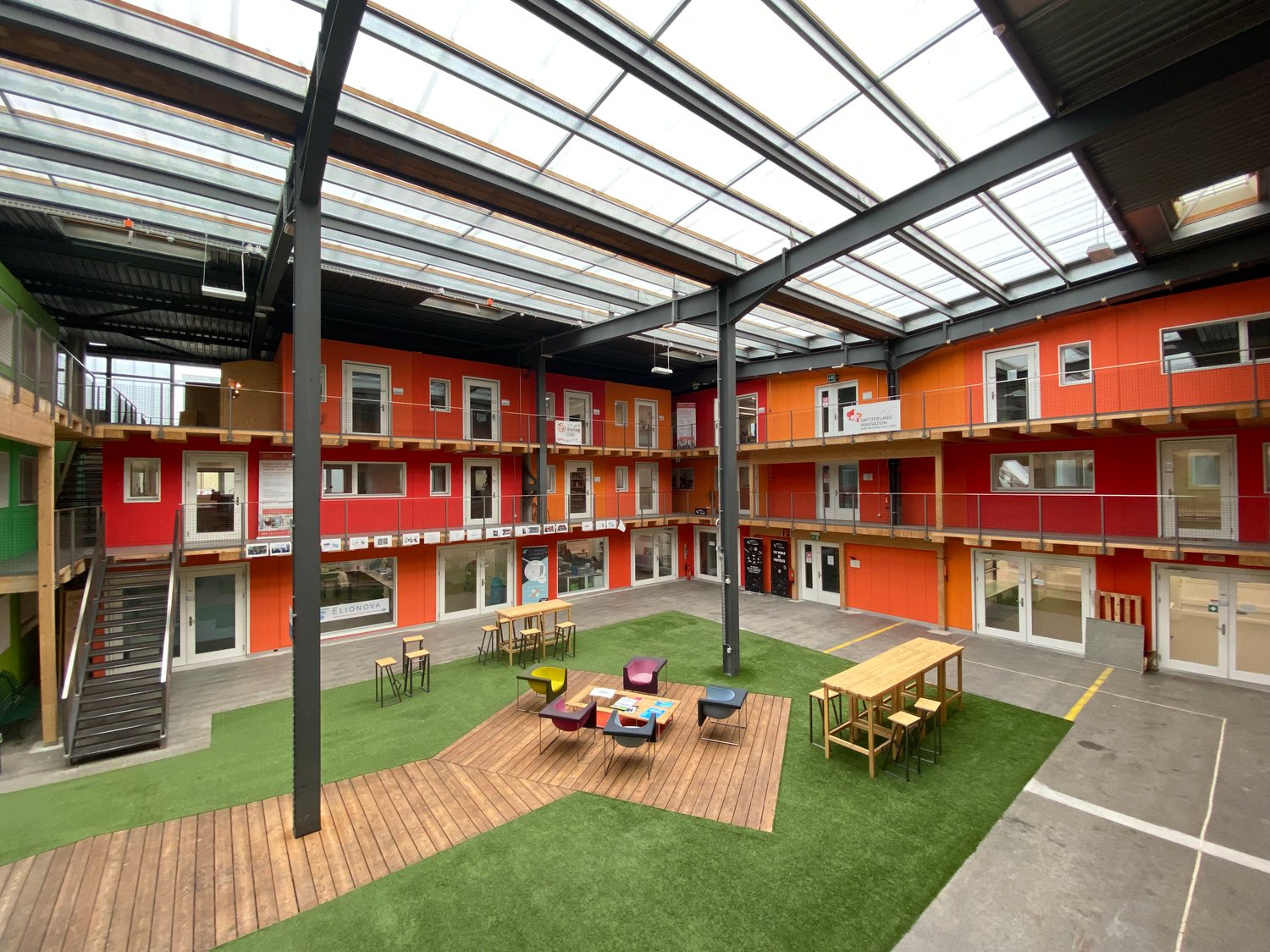modern building with multiple levels, wooden floors, green turf, communal seating area