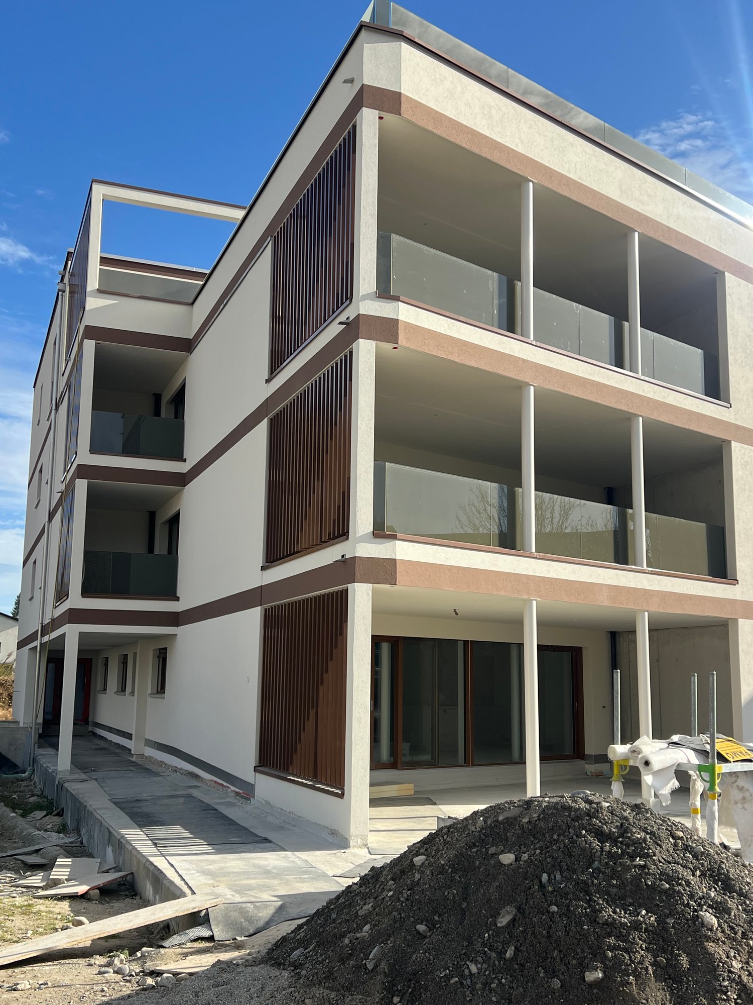 Apartment building, white and brown color, multiple floors, glass balconies, modern design