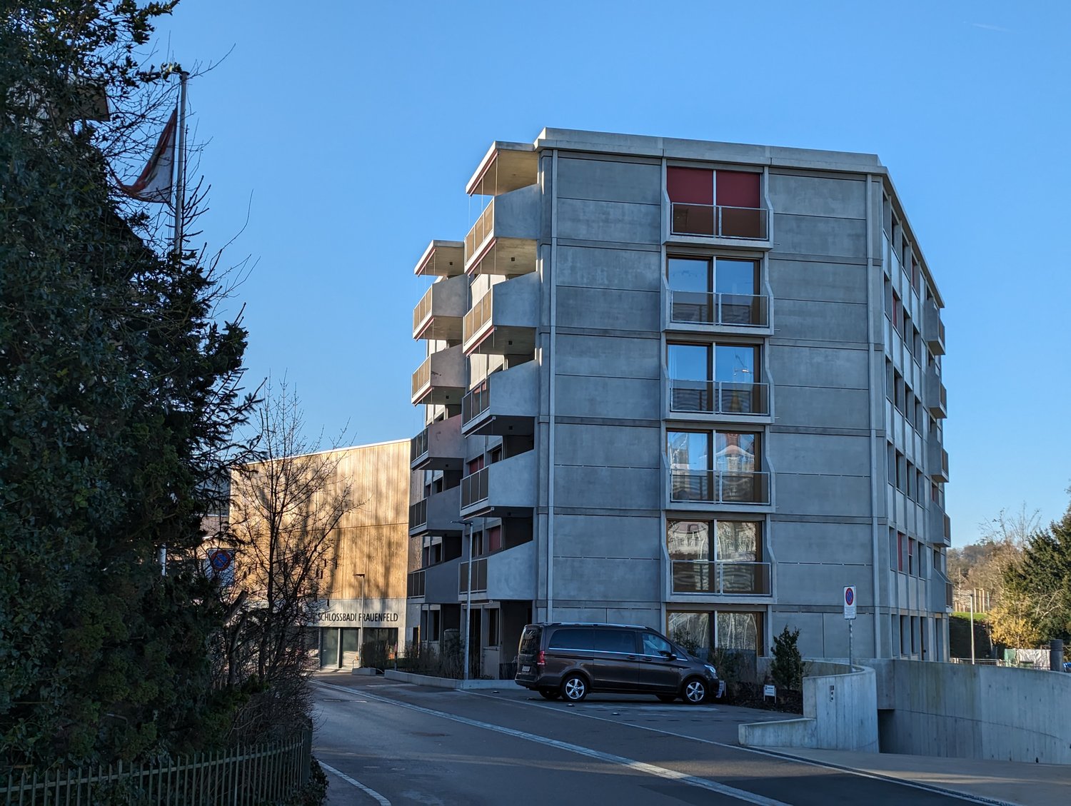 Modern residential building with balconies, multiple floors, van parked in front