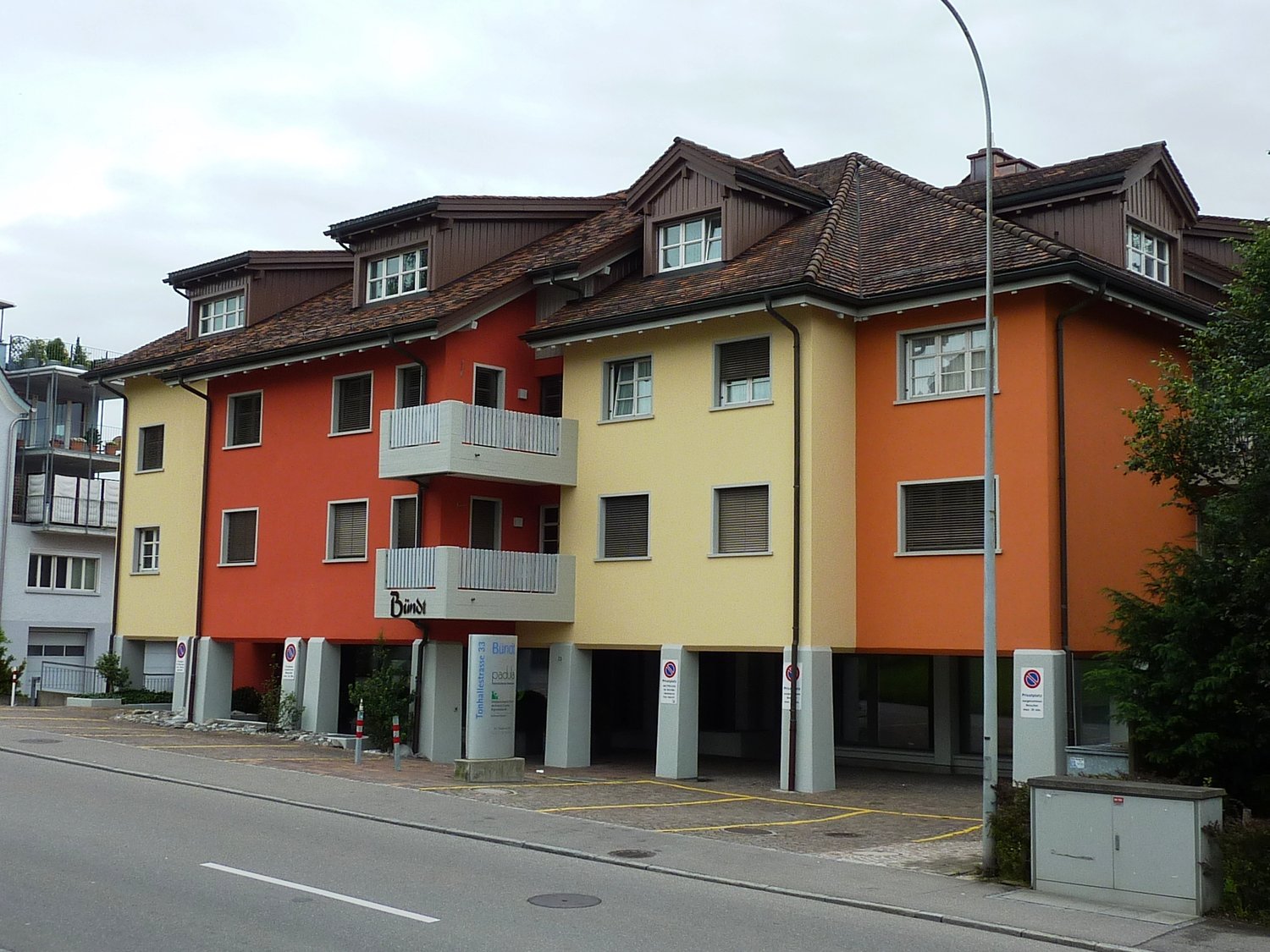 3 story building, 3 units, yellow, orange, and white paint, balconies, underground parking