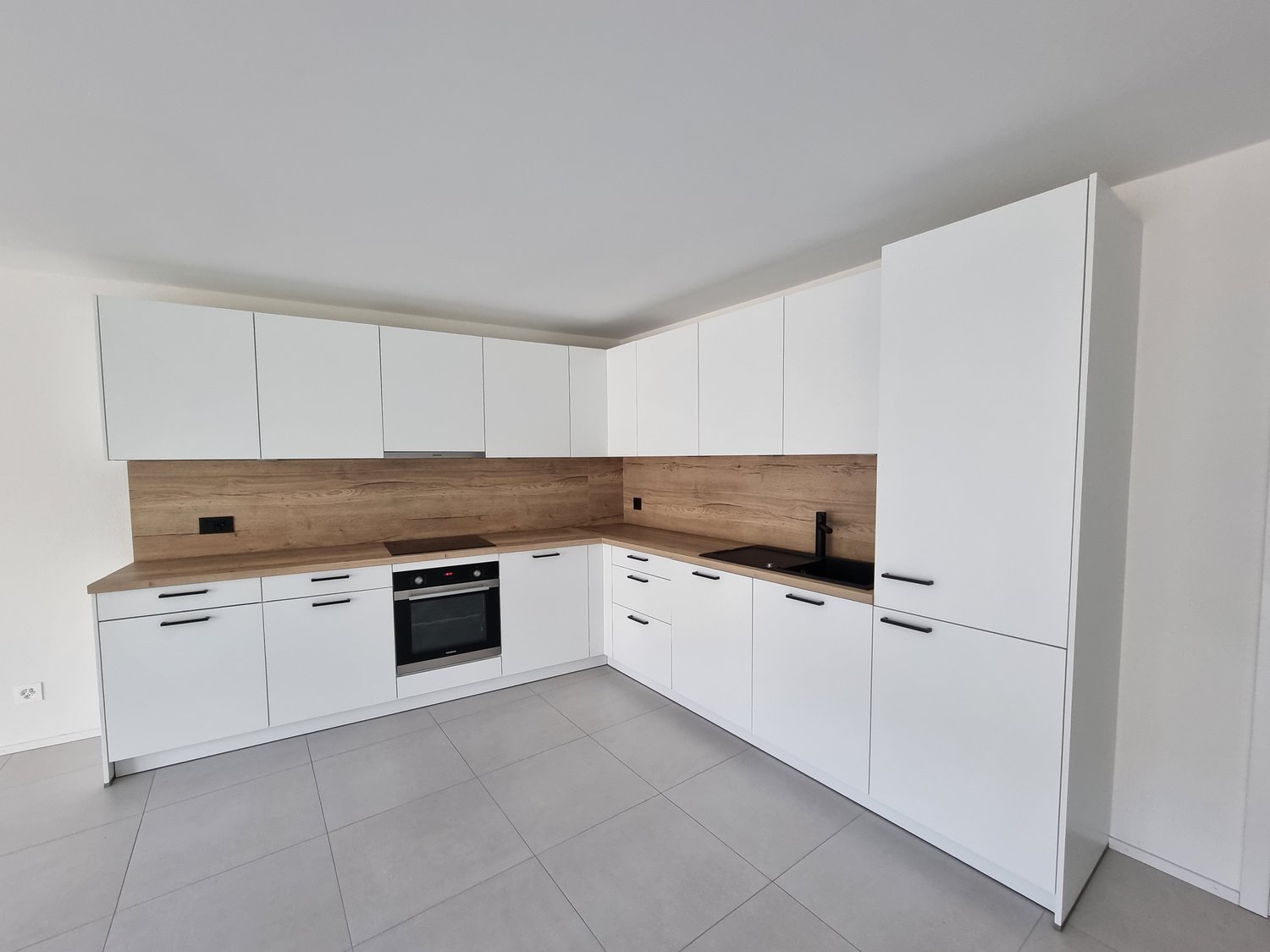 modern white kitchen with wooden countertops, white cabinets, grey tiled floor, gas stove, oven, and integrated appliances