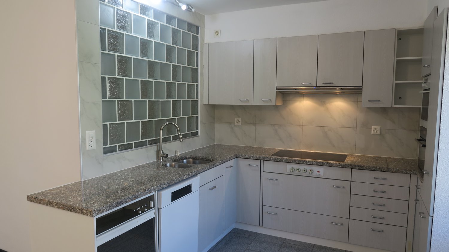 modern kitchen with granite countertops, stainless steel sink, dishwasher, electric stove, cabinets, power outlets, and a power switch