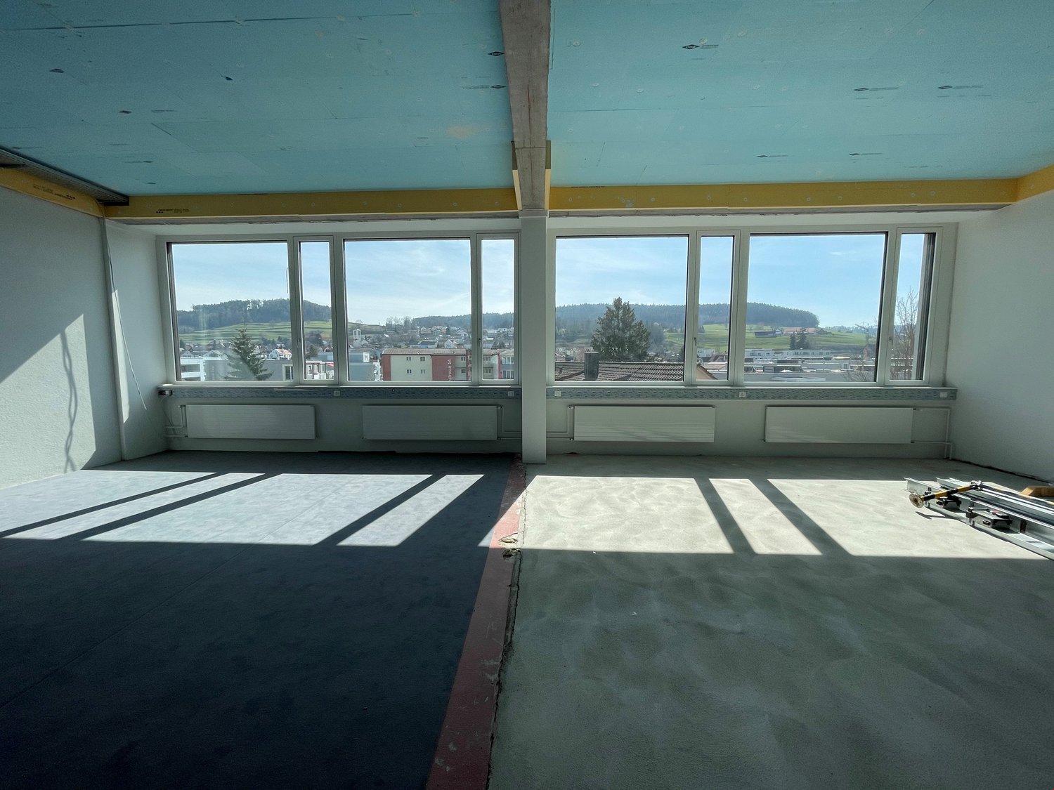 empty room, large windows, concrete floor, white walls, heating radiators