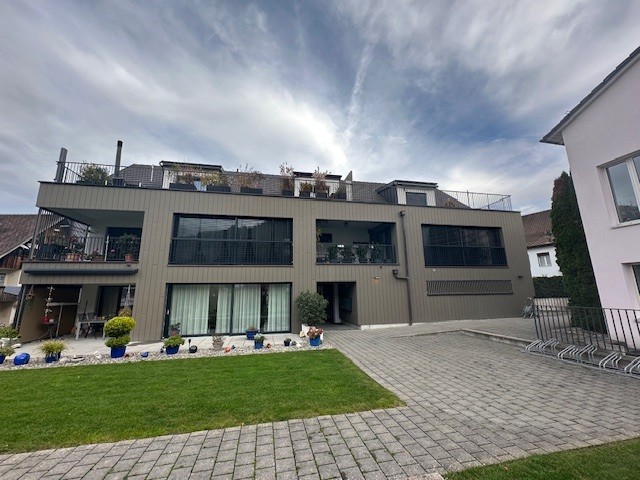 multi-story house, glass windows, balcony, plants, garden, brick driveway