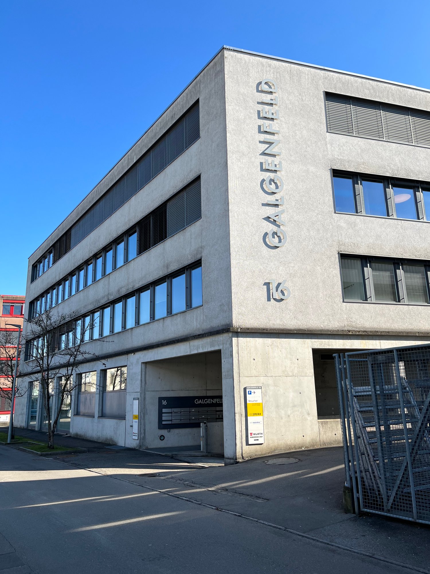 modern building with grey and black wall, multiple windows, text on wall 'GALGENFELD', grey garage entrance