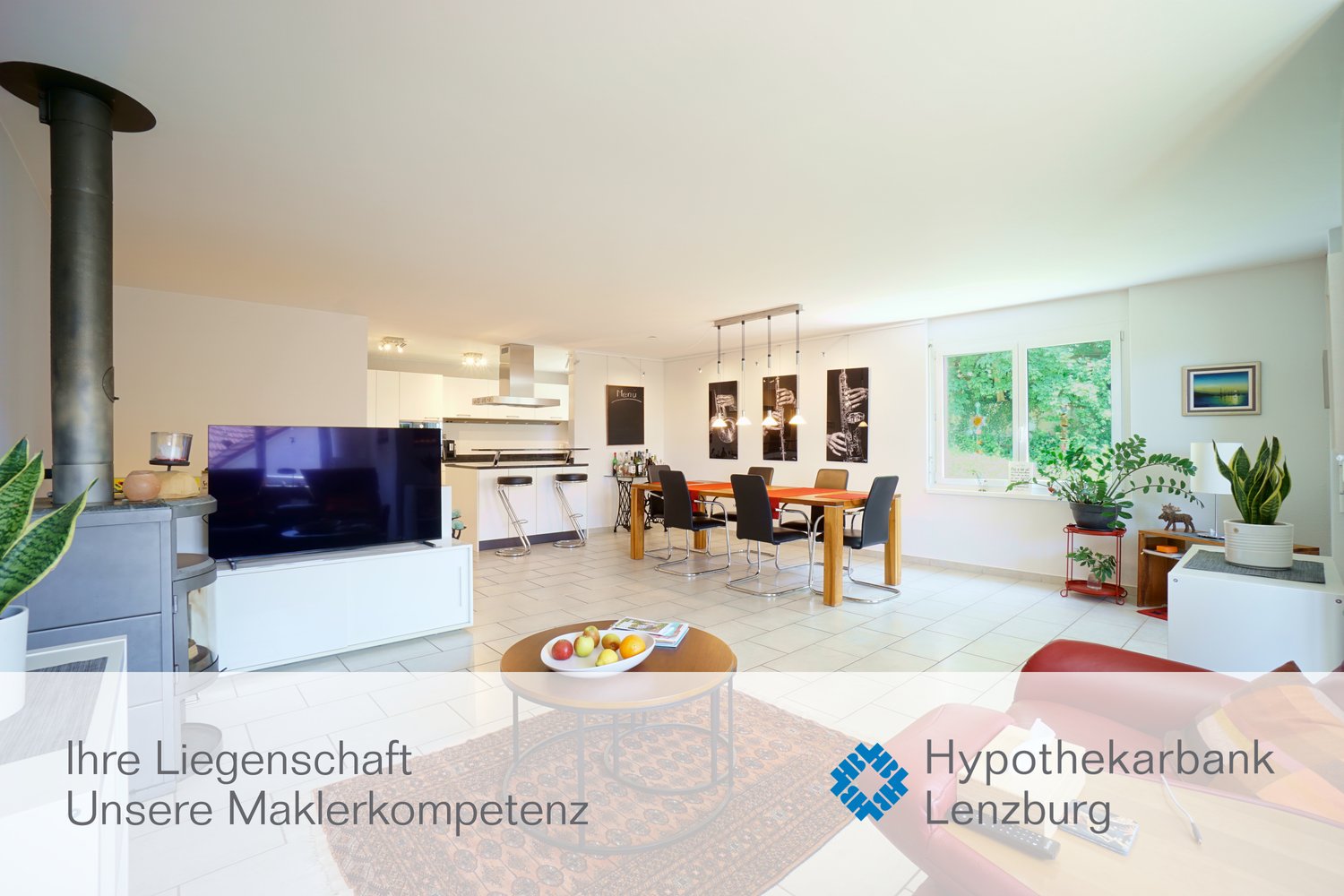 Spacious open-plan living area with kitchen, dining table, and living room. Large windows, hardwood floors, modern furniture and decor. TV, dishwasher, and various potted plants visible.