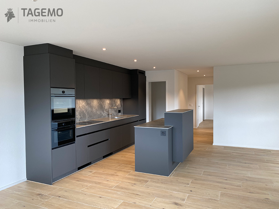 Modern kitchen, wooden floor, gray cabinets, granite countertop, integrated oven and microwave, island, open doorways, clean, minimalist