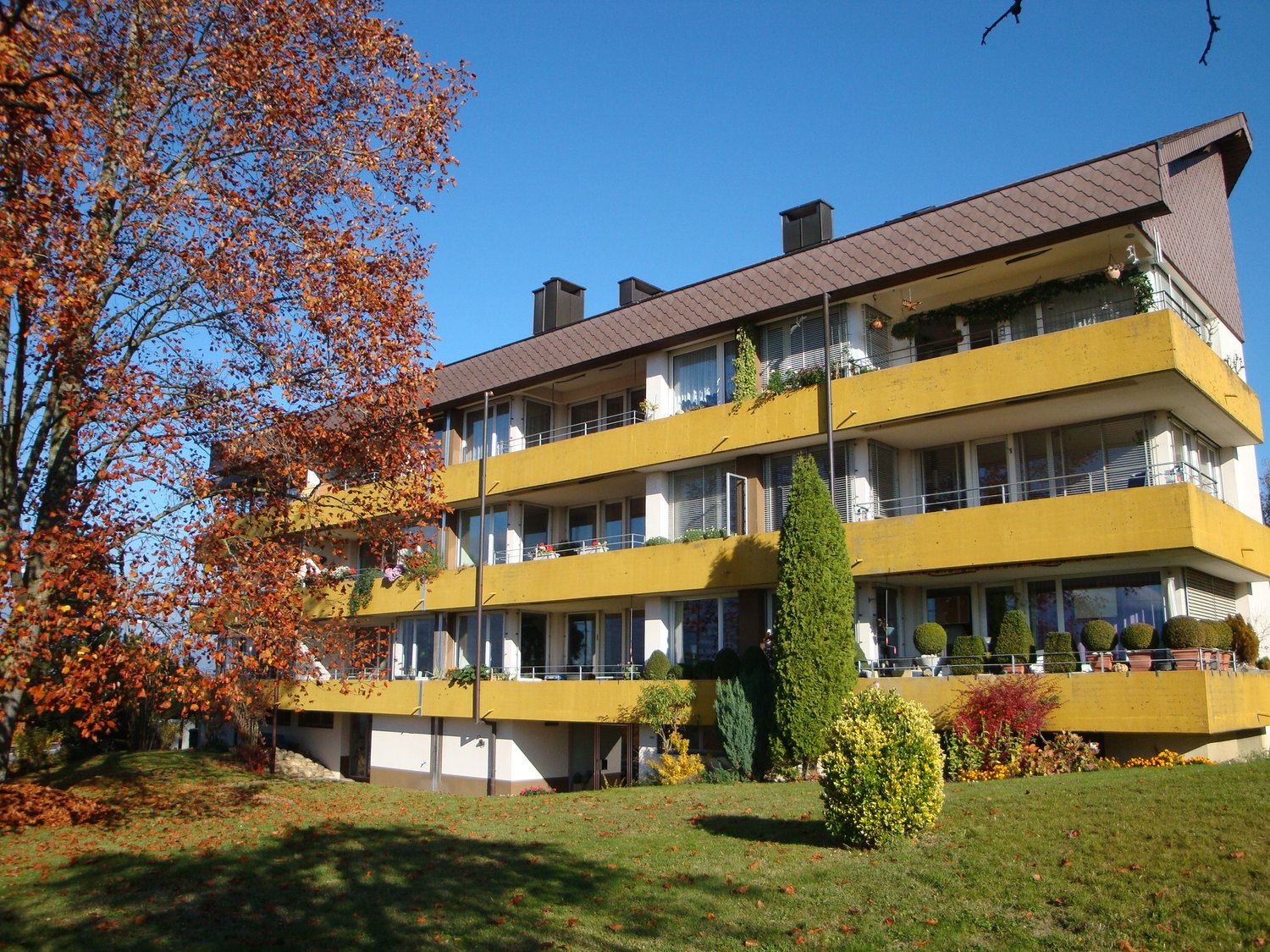 A multi-story apartment building with yellow walls, balconies on every floor, and several windows.