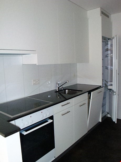 modern kitchen with white cabinets, black countertops, stainless steel sink, gas stove, oven, refrigerator, dishwasher, and a faucet