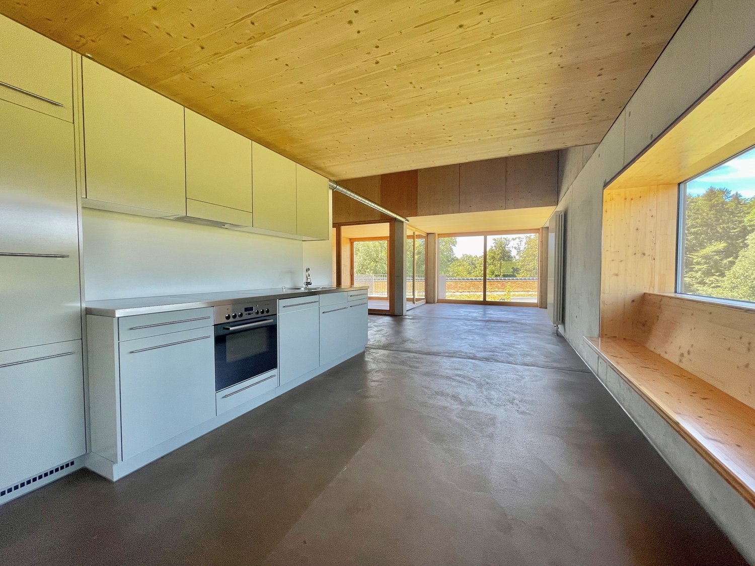 modern minimalist kitchen with open windows and bench seat, concrete floor, yellow ceiling