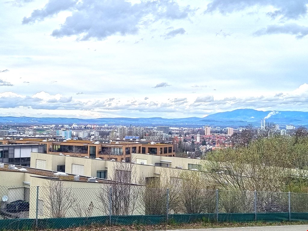 A modern building complex with beige walls, white doors, glass windows, solar panels, and metal fences.