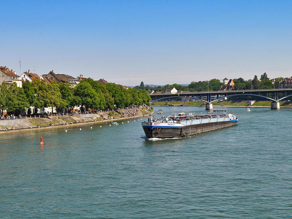 large river with trees, building, bridge, people, boat