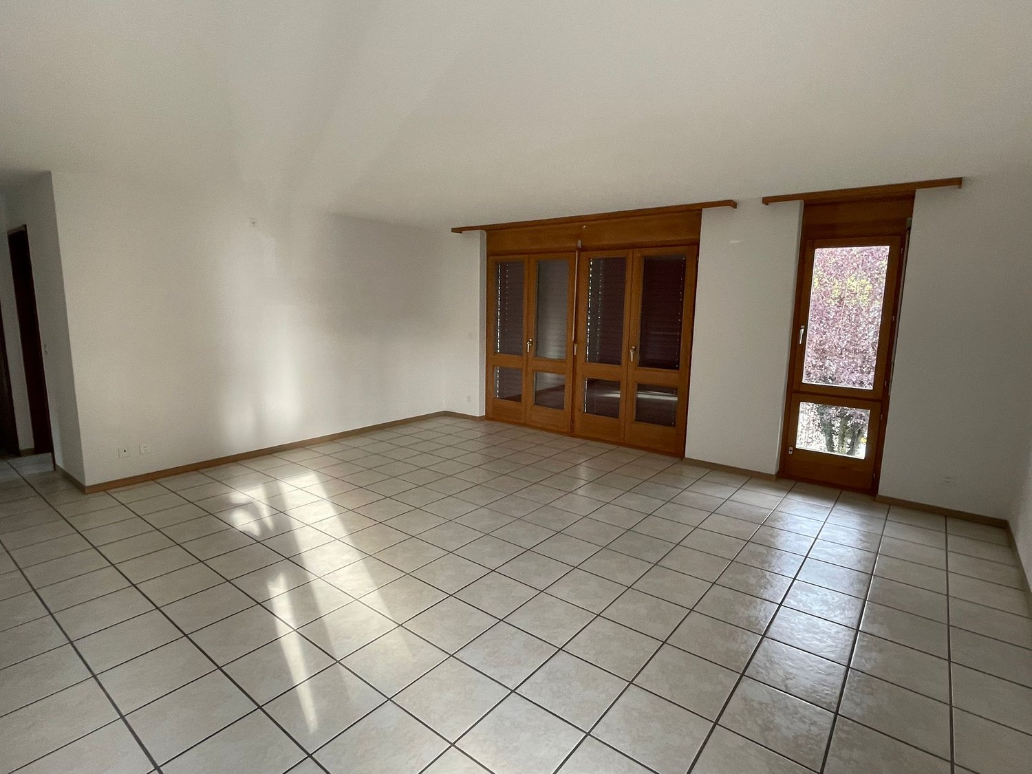 empty room, white tile flooring, wooden doors, white walls, power outlet