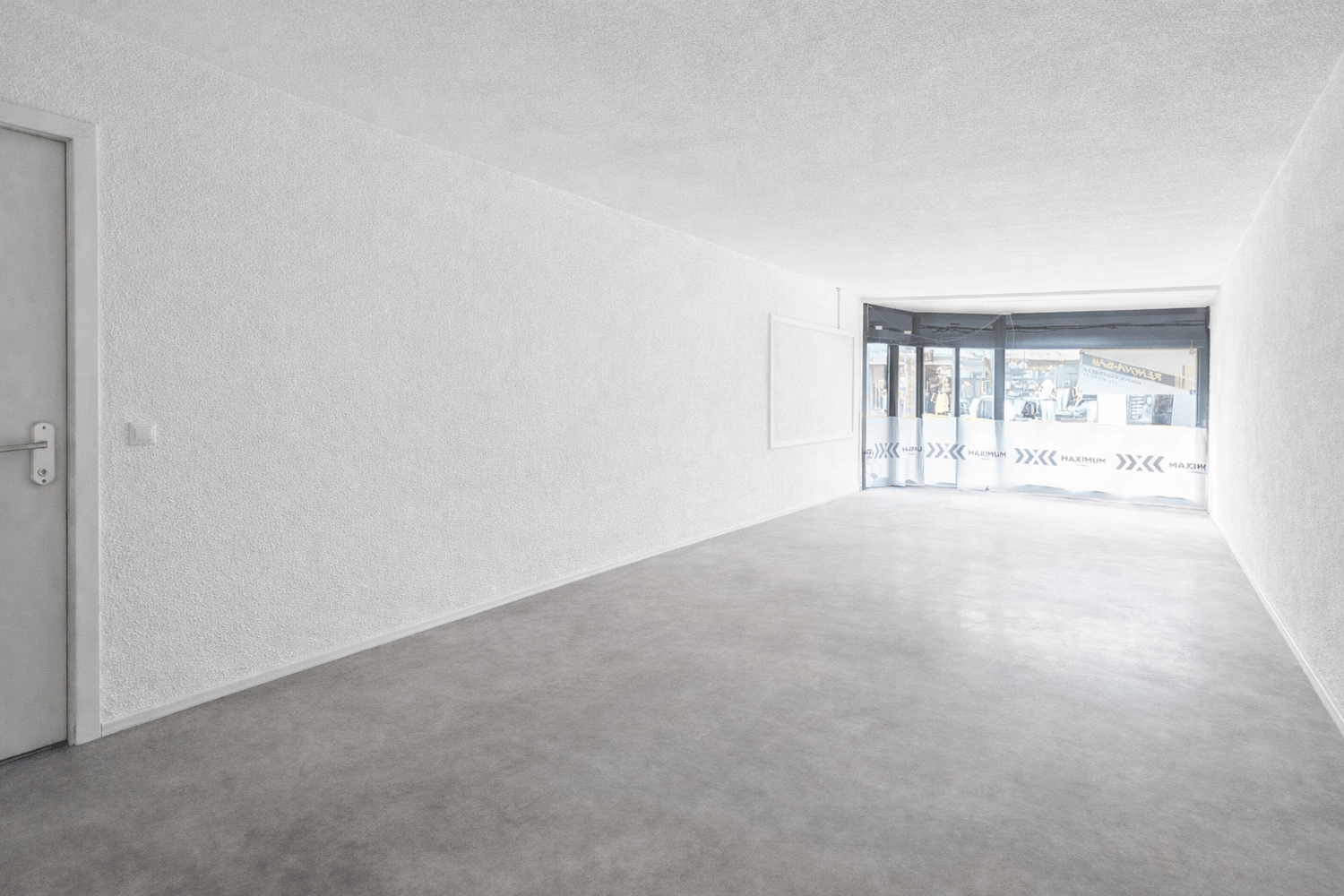 white walls, grey carpet, open door leading to outside, large windows