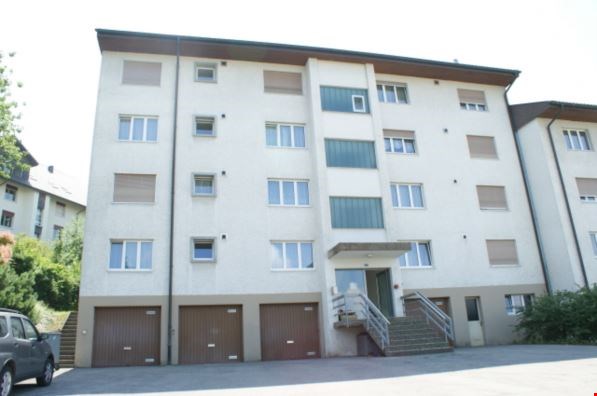 An apartment building with multiple units, each floor has 4 units, large garage for each unit, staircases lead to the entrance