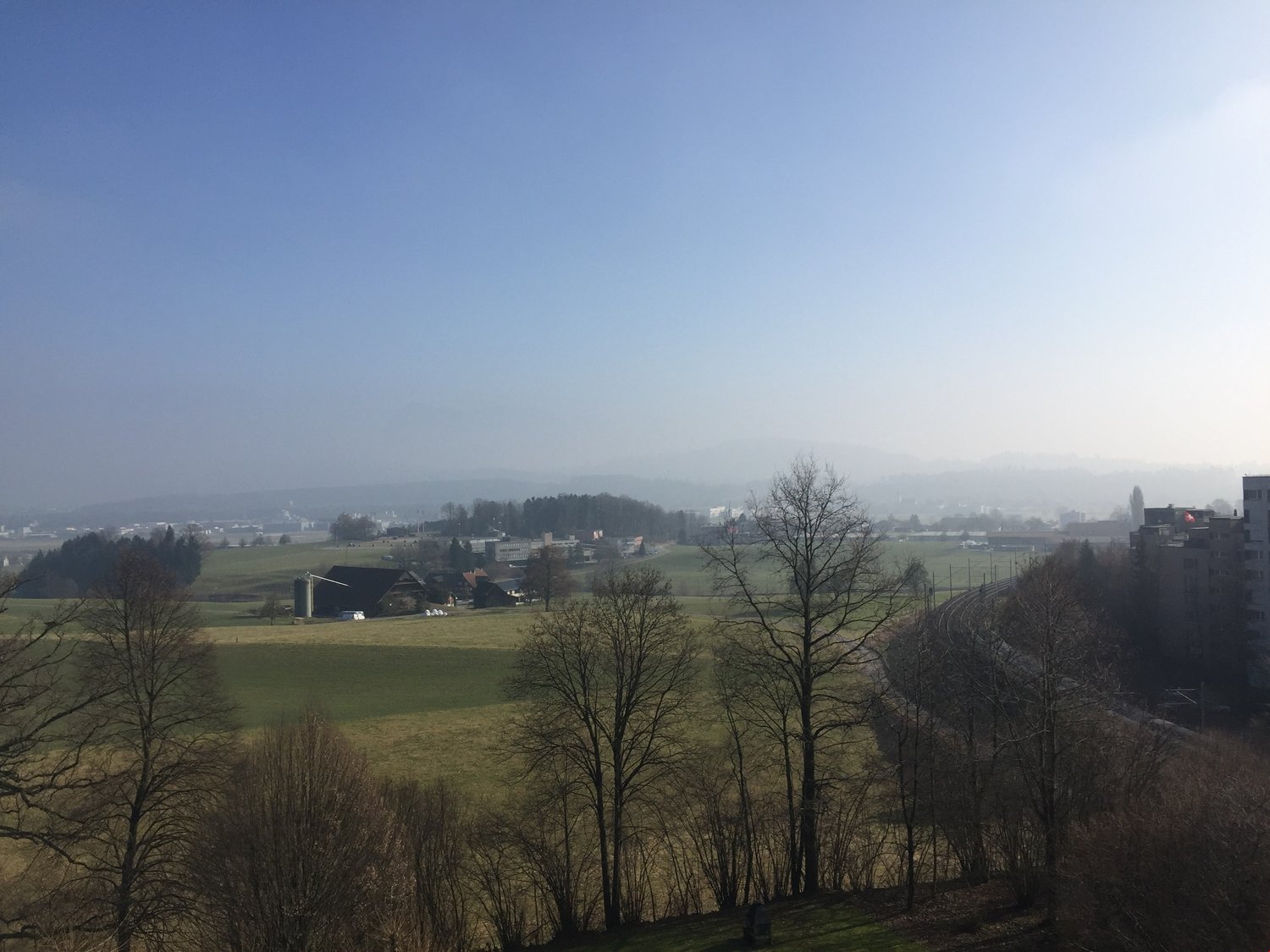 View of the countryside from a elevated location with deciduous trees.