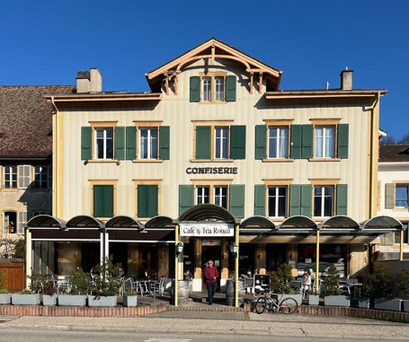 Hotel with a restaurant and tea room, red-brick facade, green shutters, a person in front of the entrance