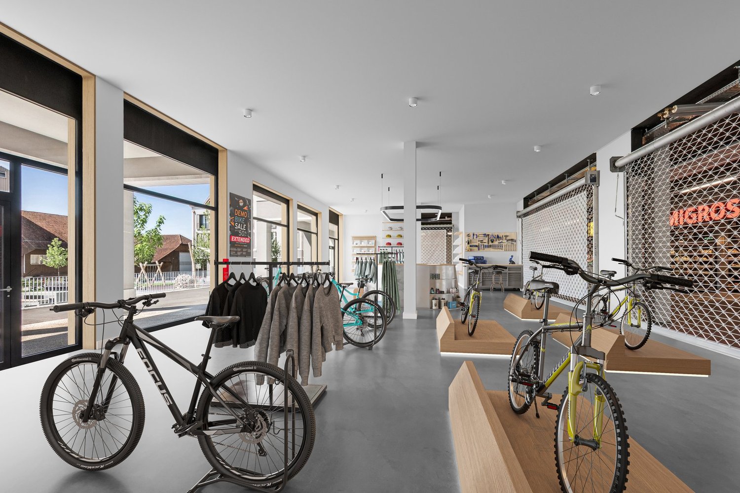 interior of a bicycle store with bikes on display, clothing racks, and large windows