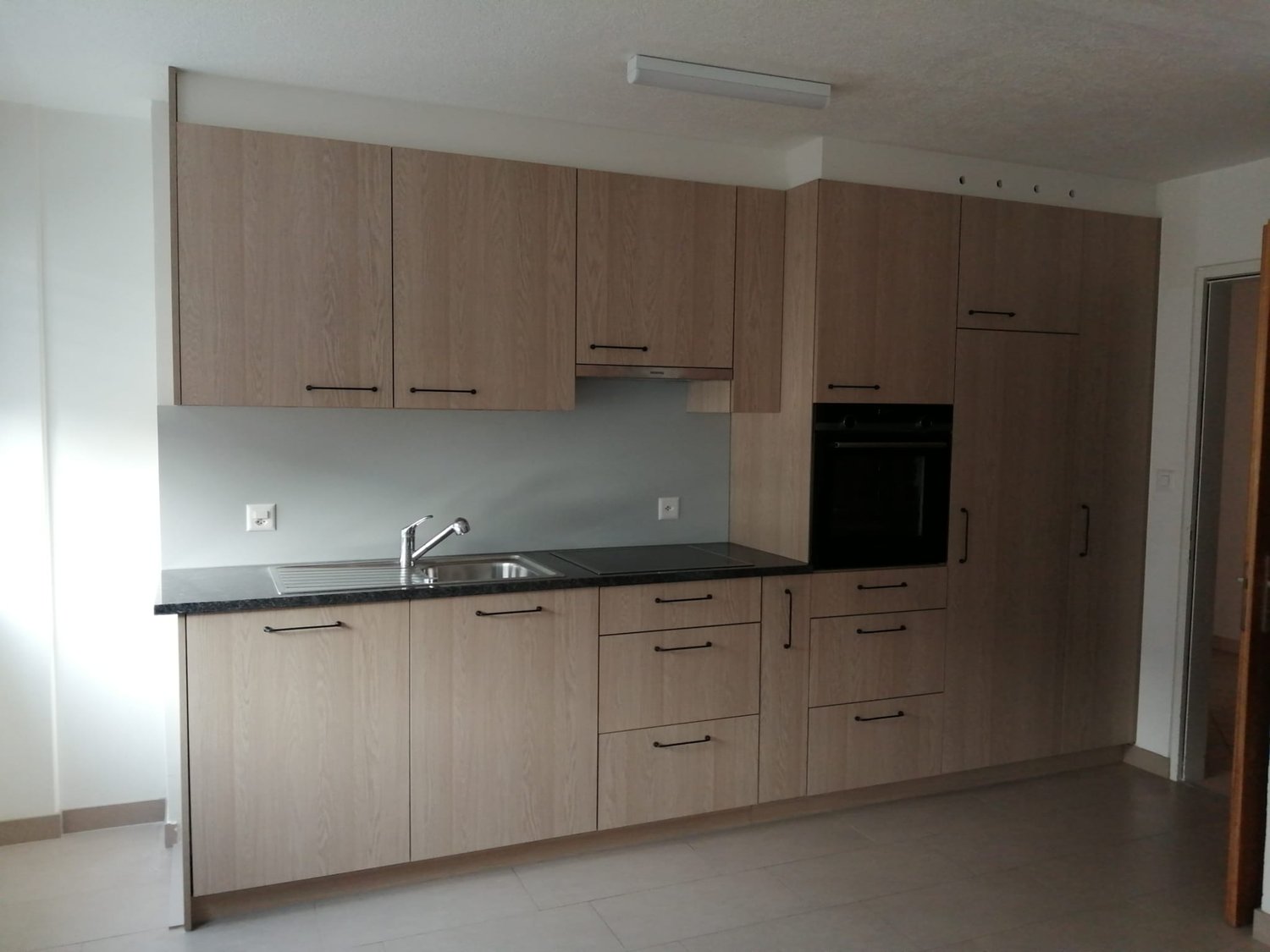 modern kitchen with built-in oven and sink, wooden cabinets, tile floor