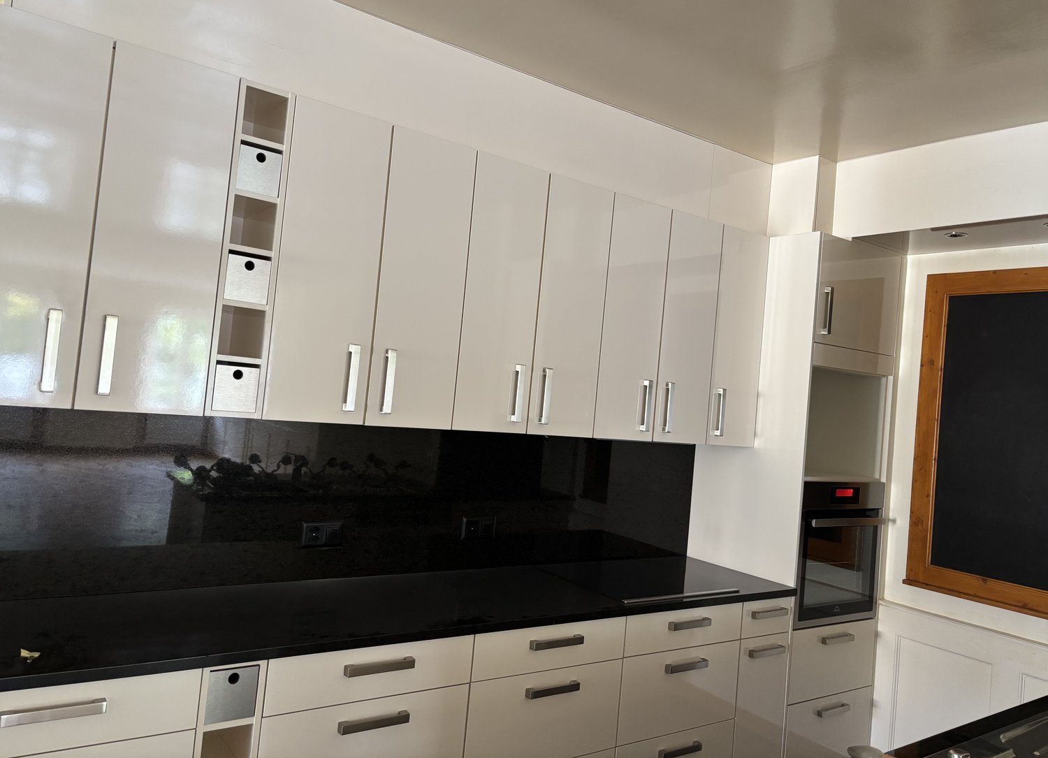 White cabinets, black countertops, gas stove, built-in oven, pull-out shelves, drawers with silver handles, modern design