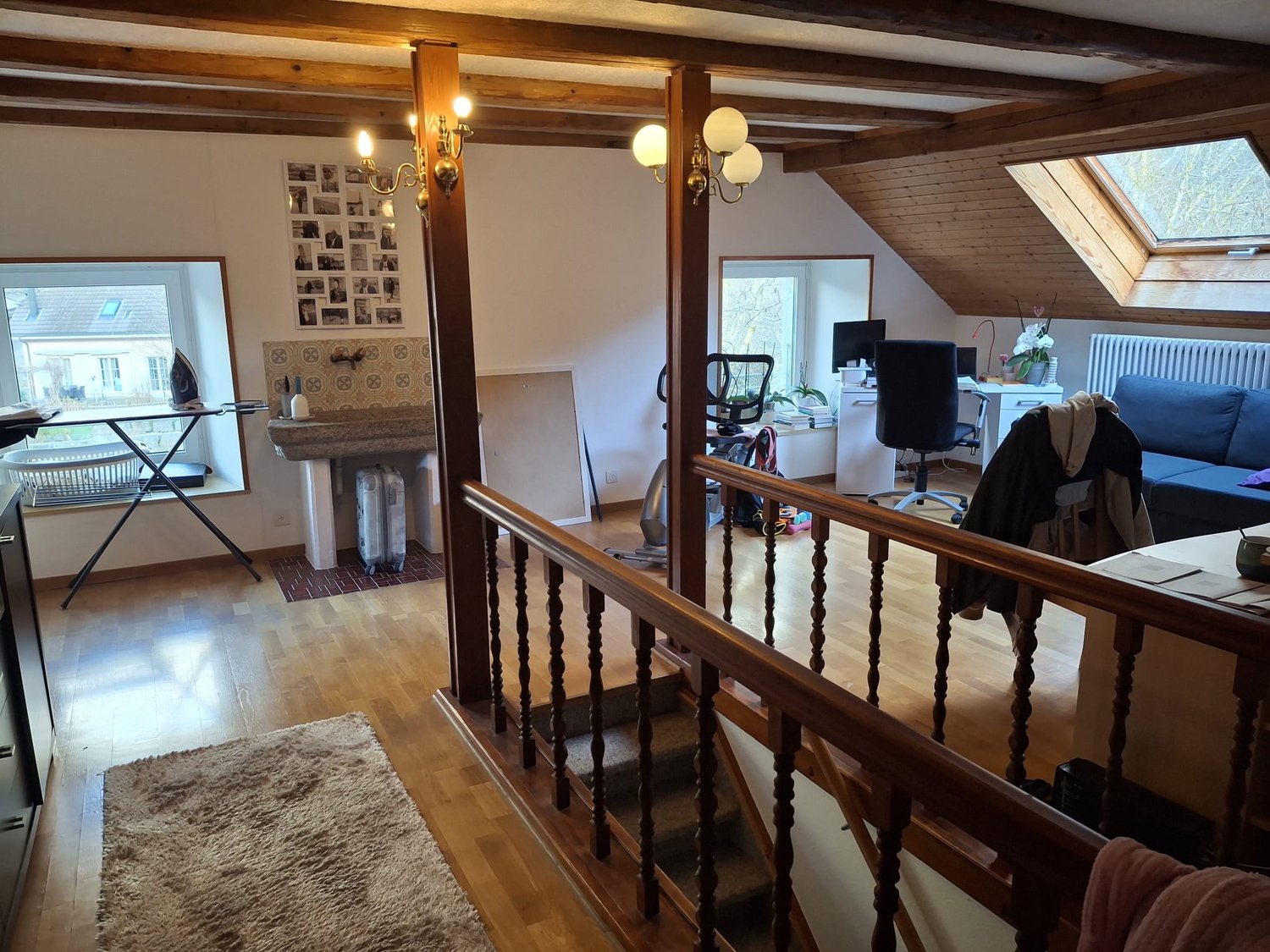 high ceiling, open space, wooden floor, balcony, office desk and chair, clothes and books, window, ladder leading to upper floor