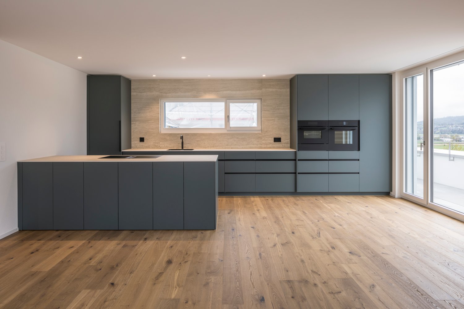 modern kitchen with island, wooden floor, gray cabinets, white countertops, built-in oven, sink, and faucet