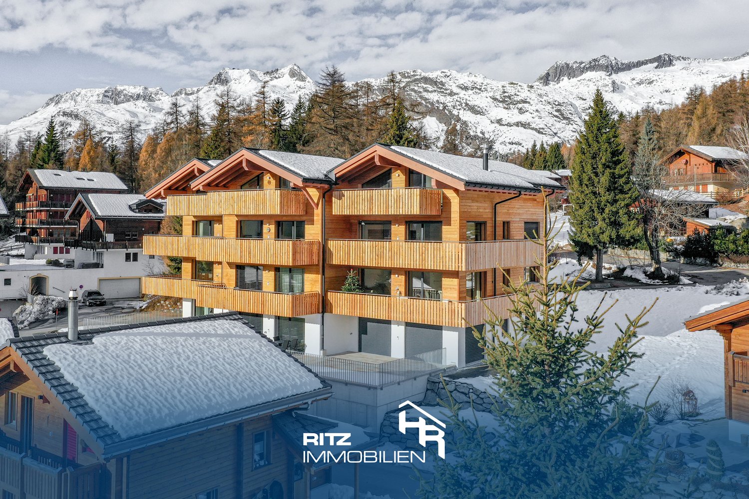 3-story building, wooden exterior, balconies, snowy mountains in the background