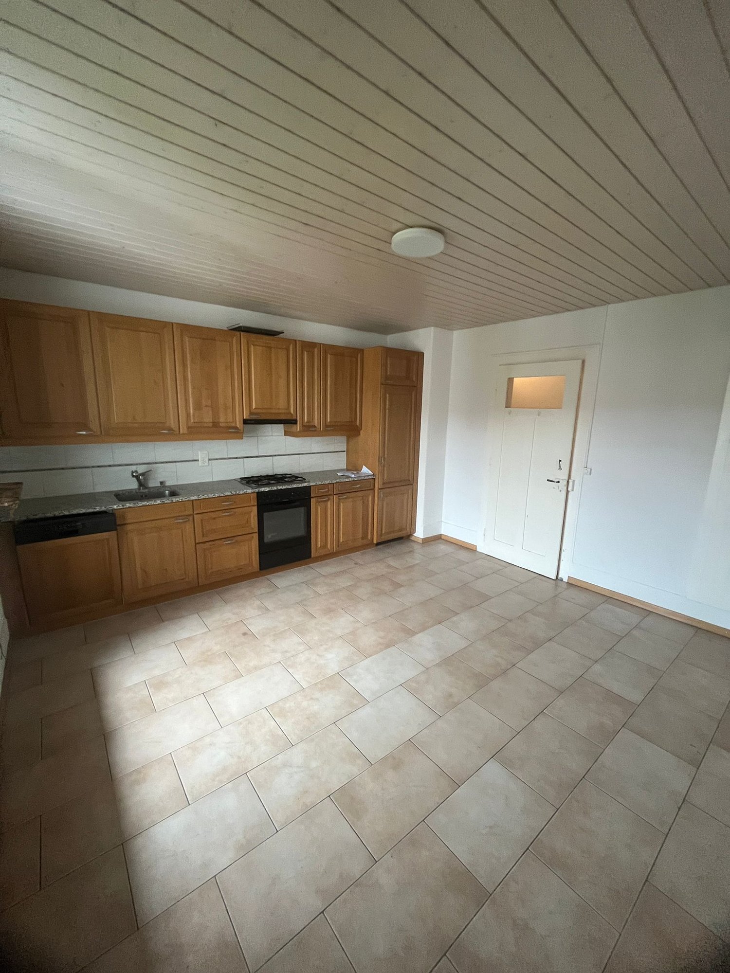 Spacious kitchen with wooden cabinets, tile flooring, and a dishwasher