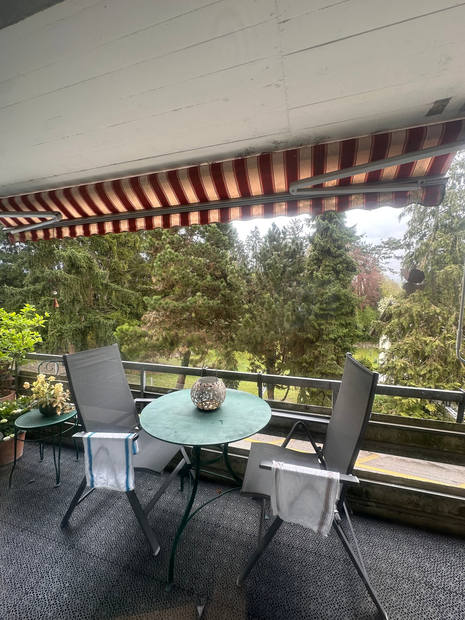 Balcony with a table, chairs, and a canopy, overlooking a grassy field and trees