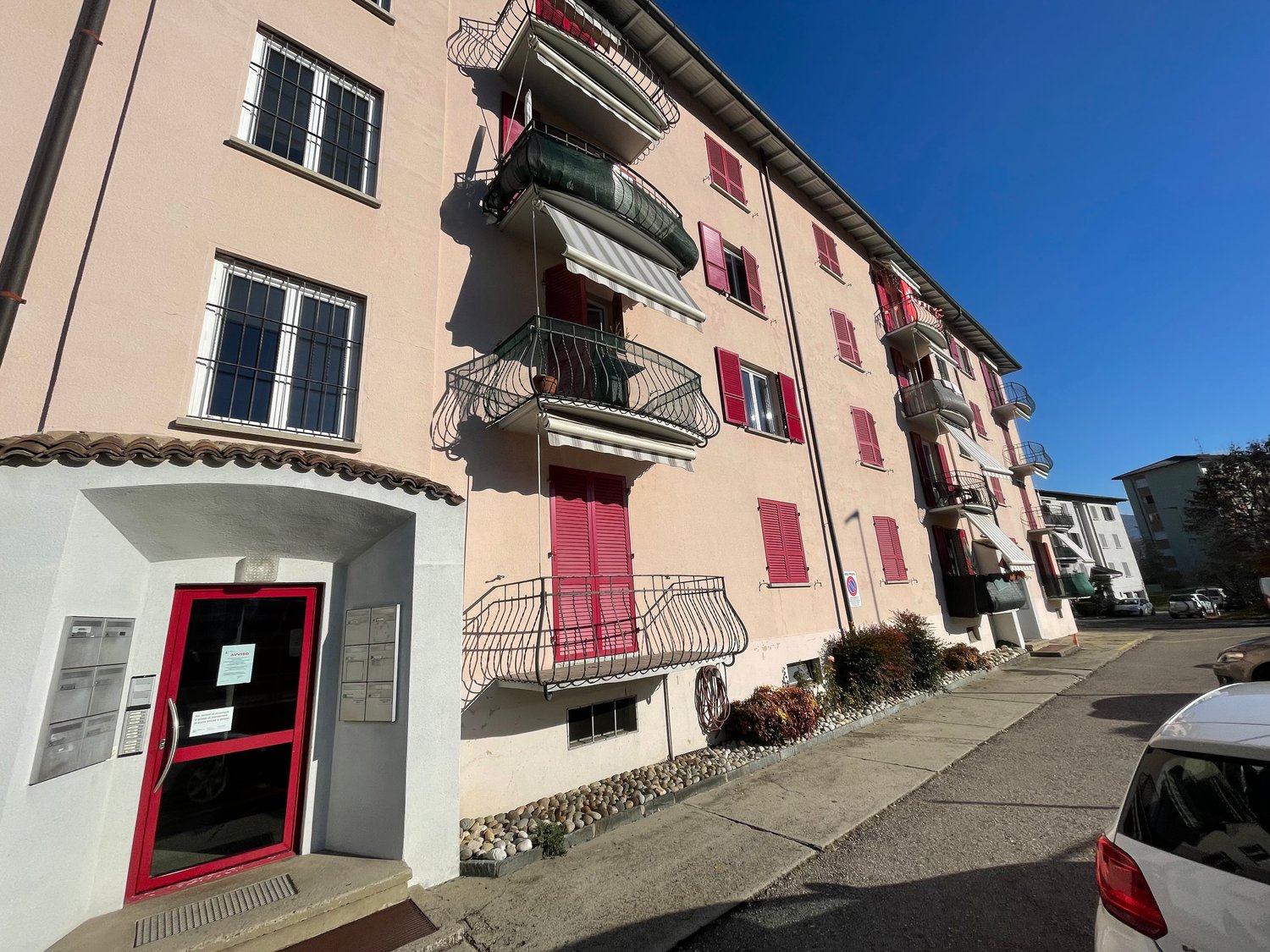 multi-family apartment building, balconies, red doors, mailbox area, fenced in front