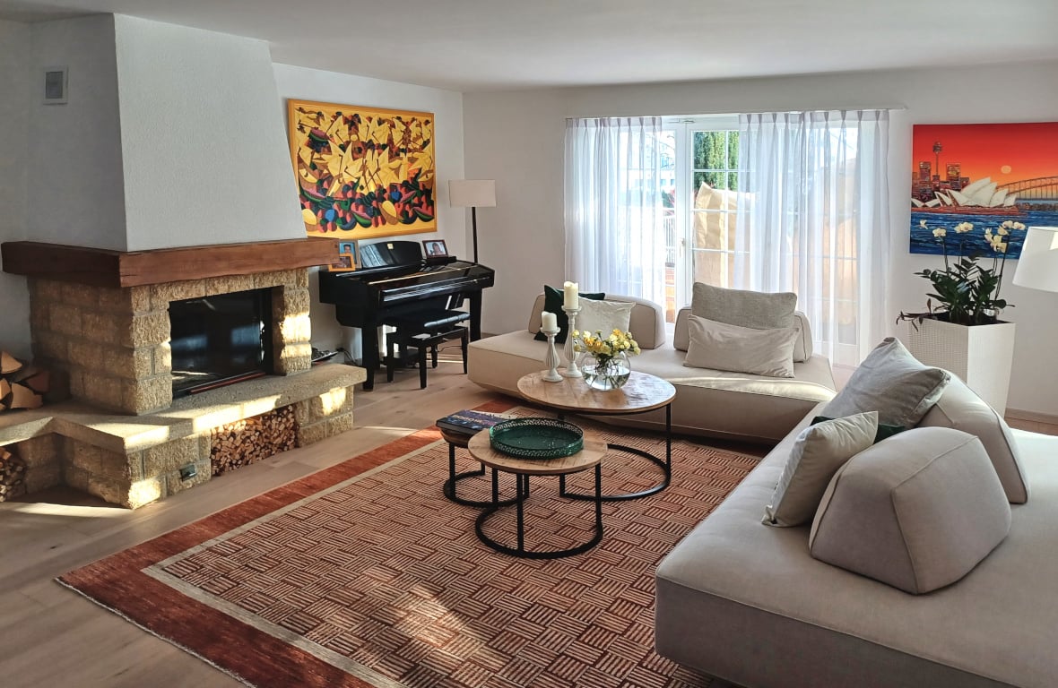 Fireplace, piano, two sofas, coffee tables, rug, paintings, lamp, plant