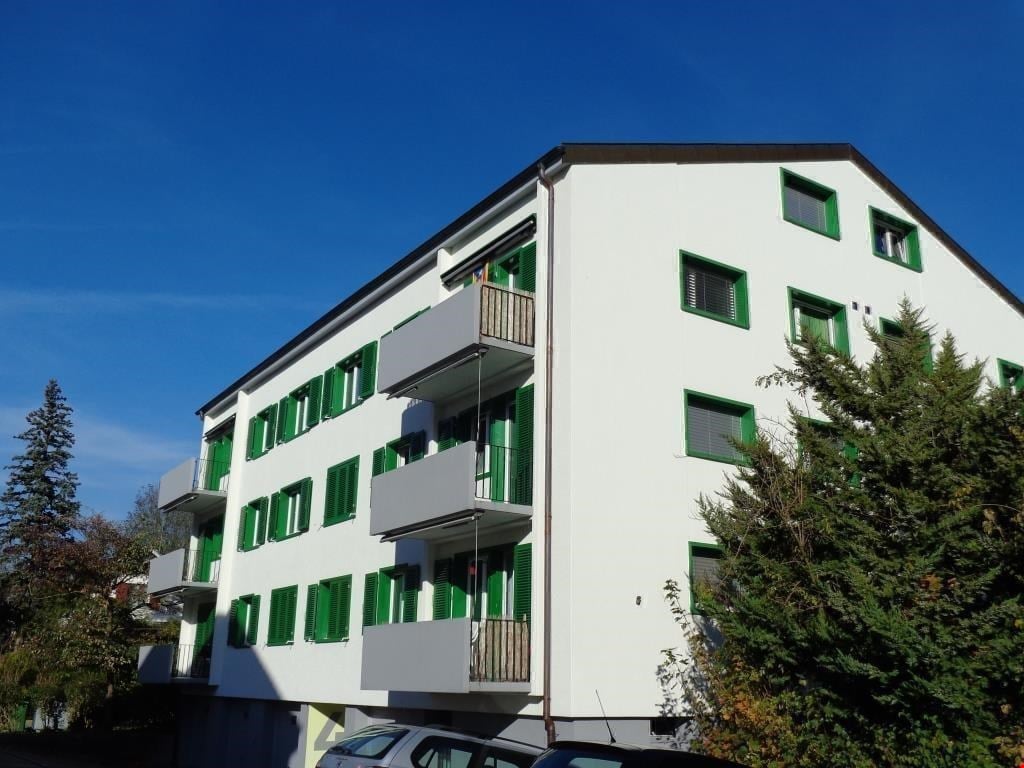 white building, green shutters, balconies, trees