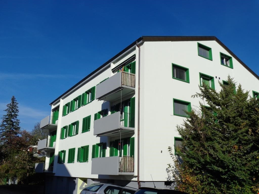 white apartment building, green shutters, balconies on every floor