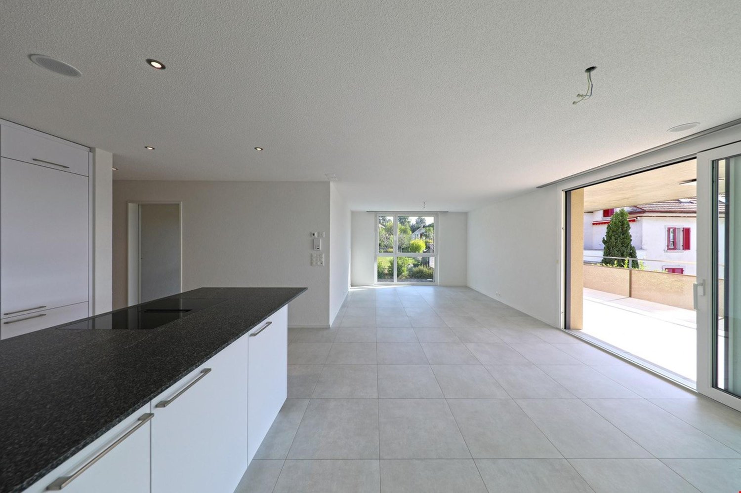 modern kitchen, tile flooring, sliding glass doors, large countertop, white cabinets, balcony