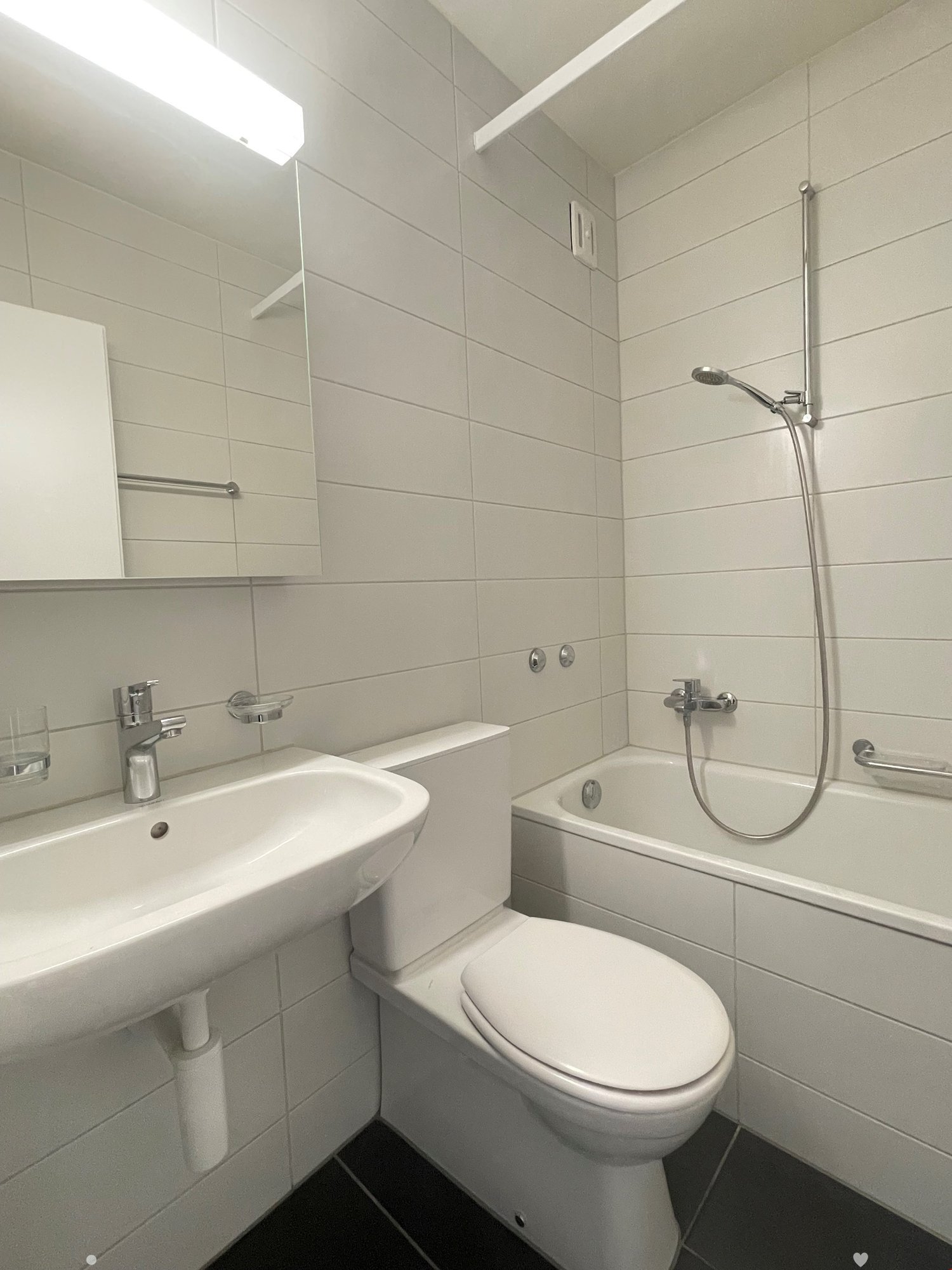 modern white tiles, bathtub, toilet, sink, overhead shower, mirror