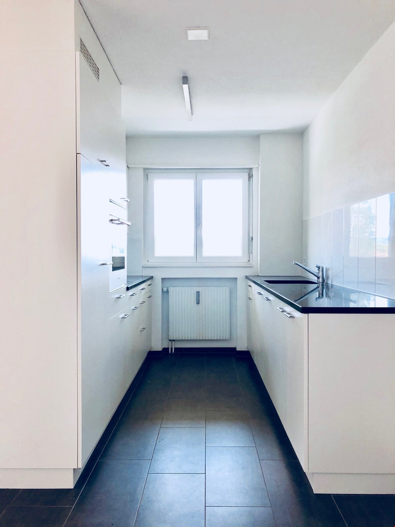 modern kitchen, black tiled floor, white cabinets, stainless steel sink, double sink, gas heating unit