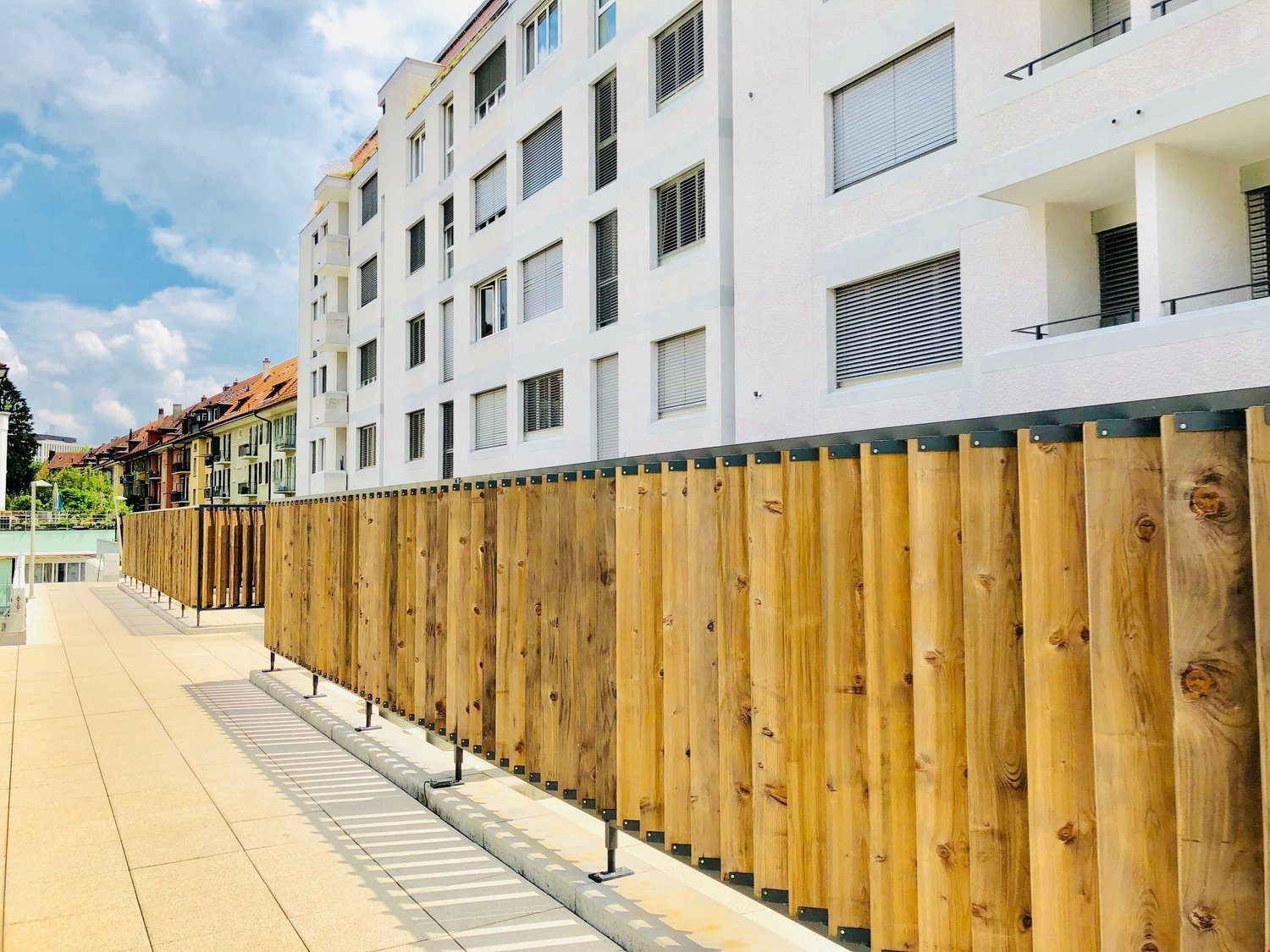 Building with white facade, multiple balconies, wooden fencing