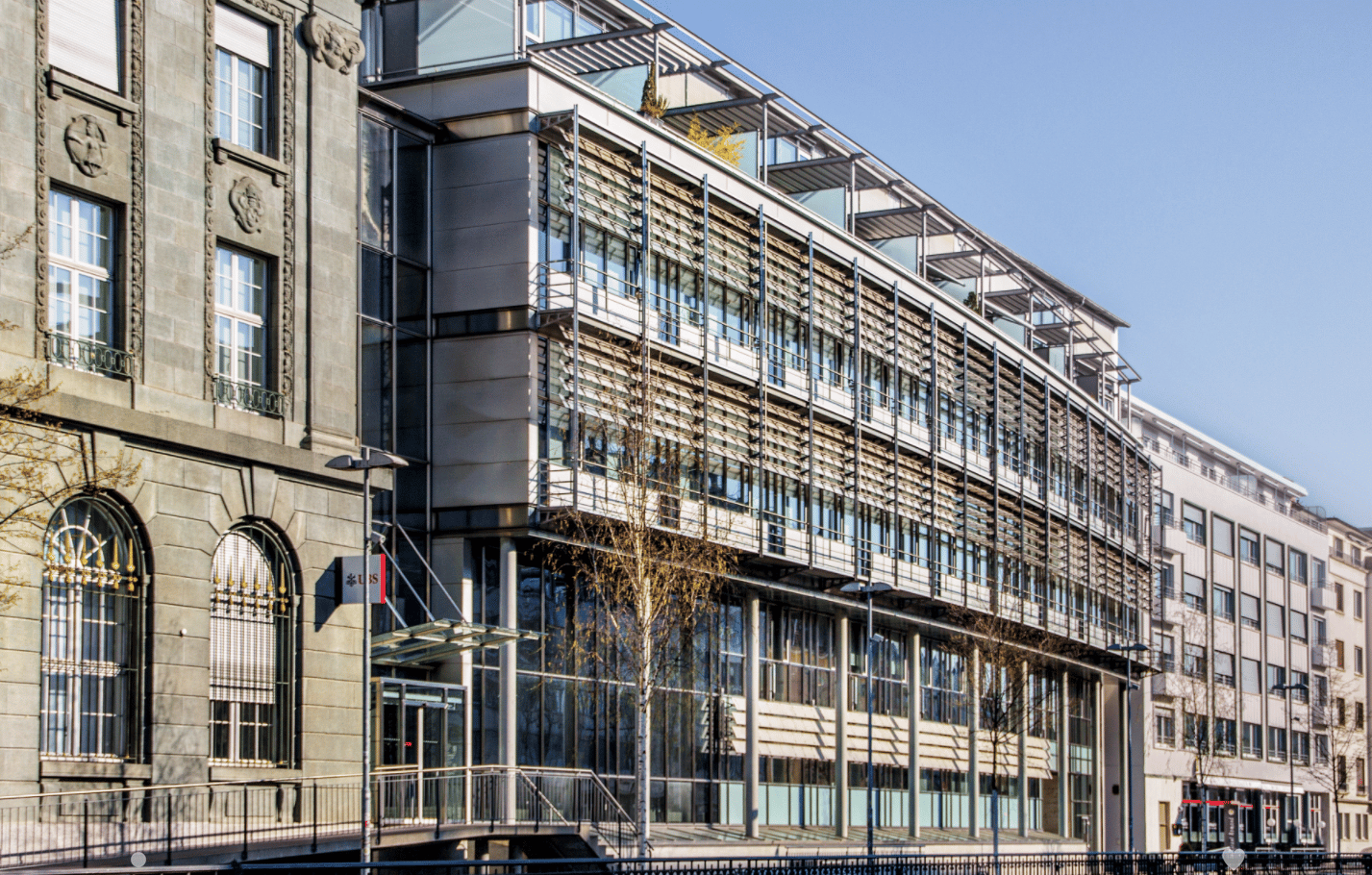 Gray building, large windows, metal railings, balcony, glass entrance, street lamp