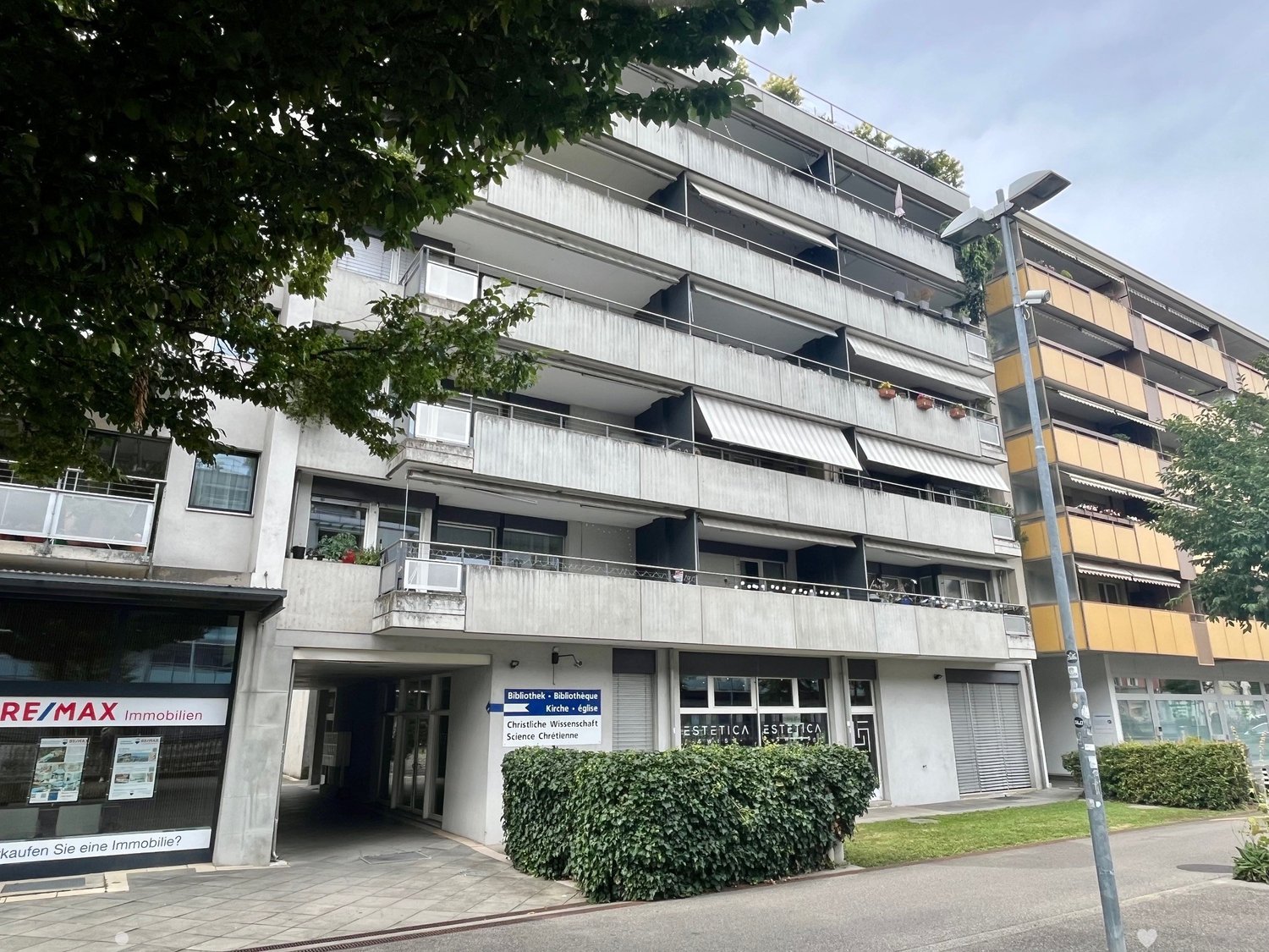 multi-story building, balconies, windows, air conditioners, entrance, sign