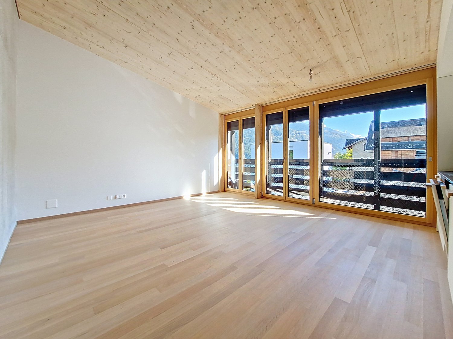 room with hardwood floors, large windows, wooden balcony