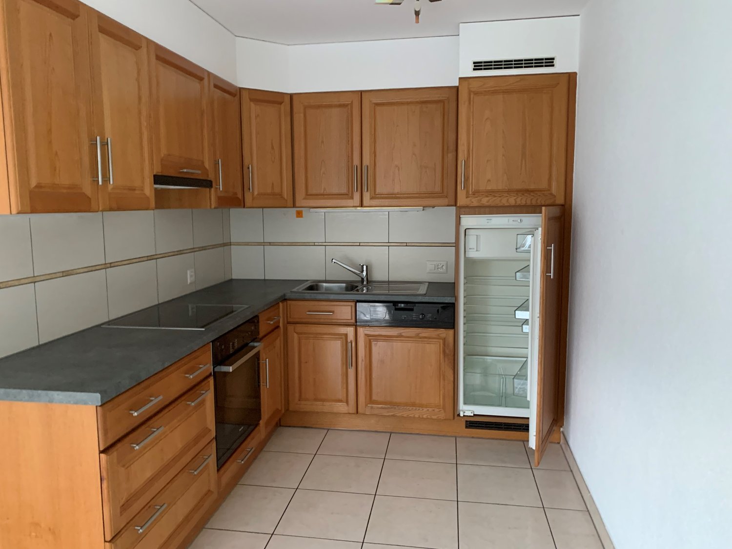 well equipped kitchen with tiled floor and wooden cabinets, stainless steel appliances, open refrigerator