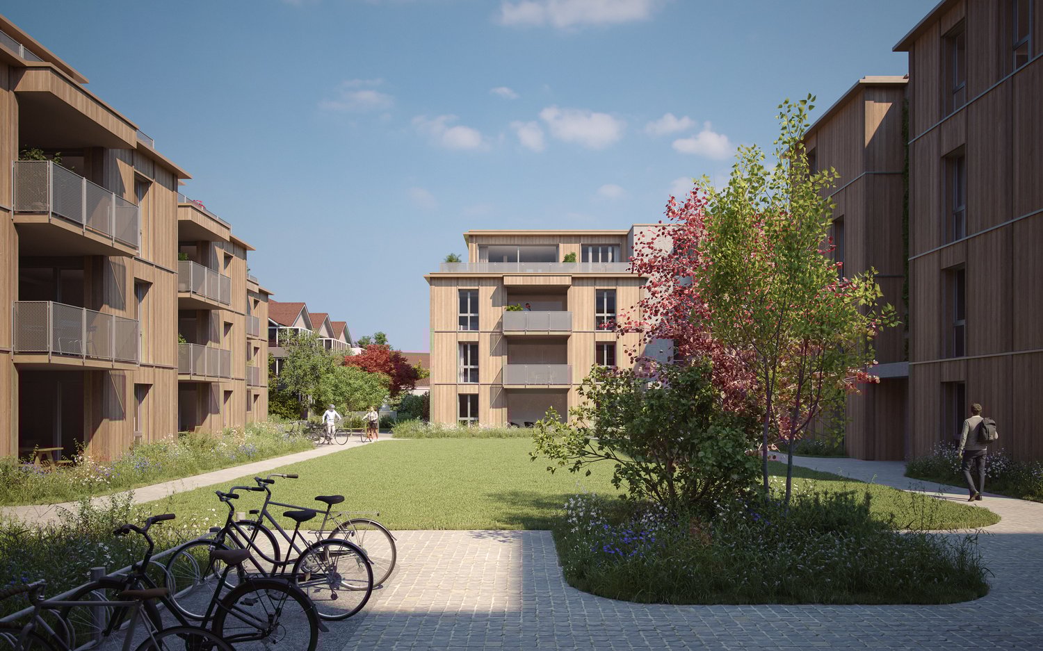 Modern apartment buildings with balconies, landscaped area with trees, a green lawn, and a paved pathway for bicycles