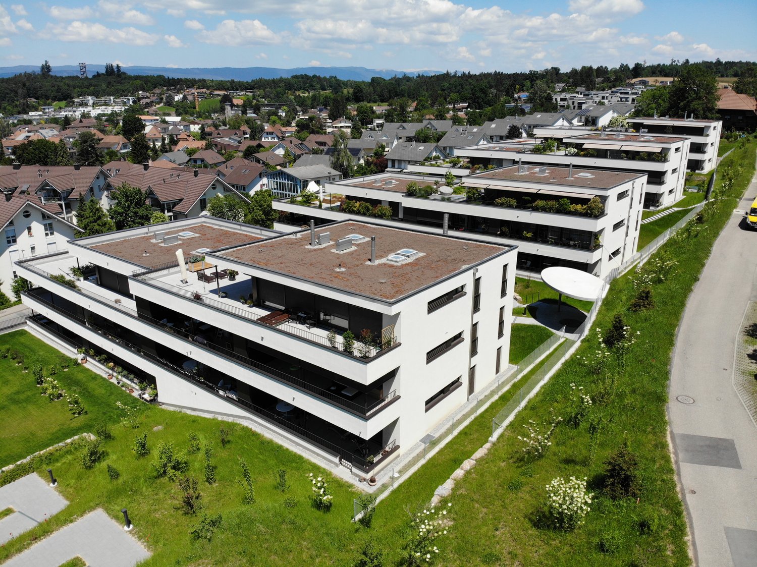 Multistory building, modern design, green rooftop, balconies, swimming pool, paved path, lush greenery
