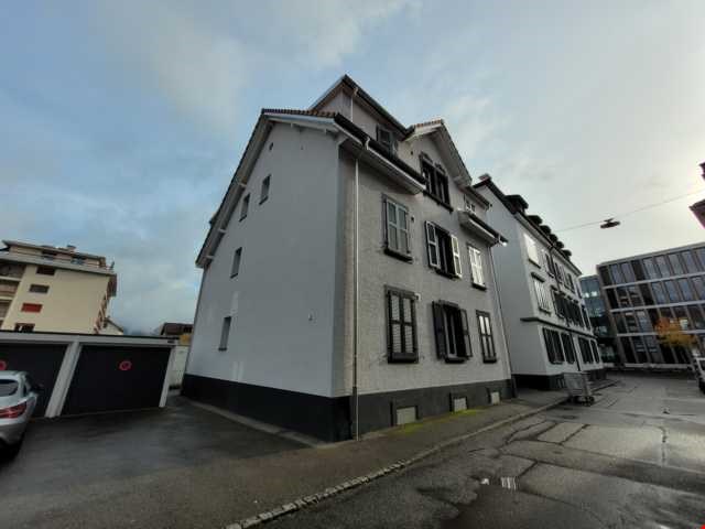 3 story building, gray exterior, multiple windows, two garages