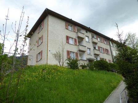 4 story apartment building, red shutters, white walls, located on a slope
