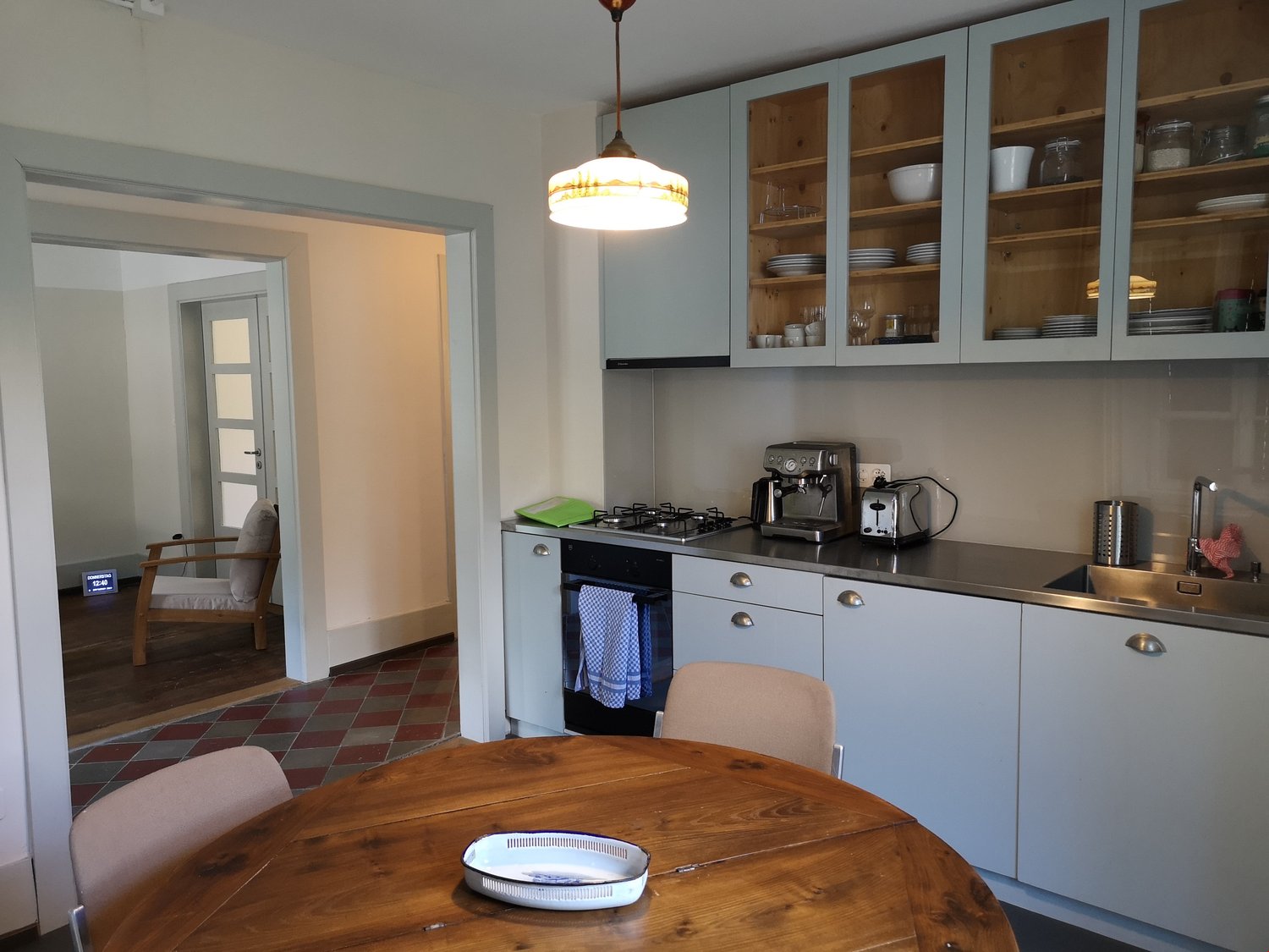 white cabinets, wooden floor, modern appliances, dining table, chairs, sink, tiled backsplash