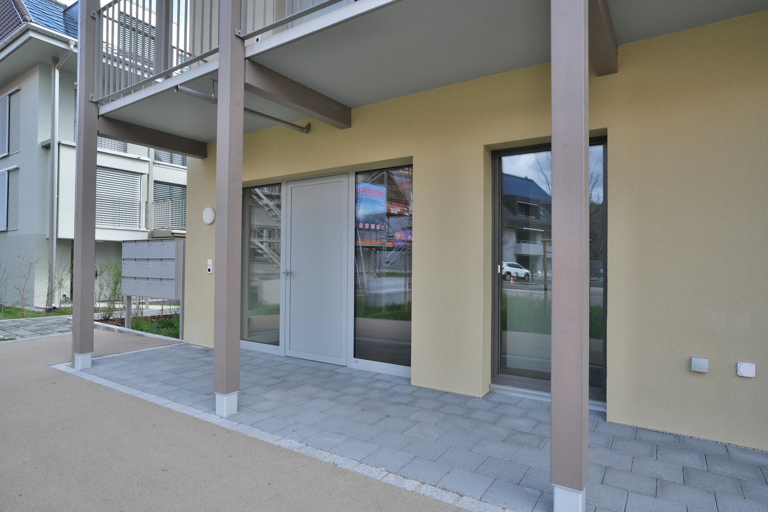 Modern building with glass doors, balcony, and mailbox