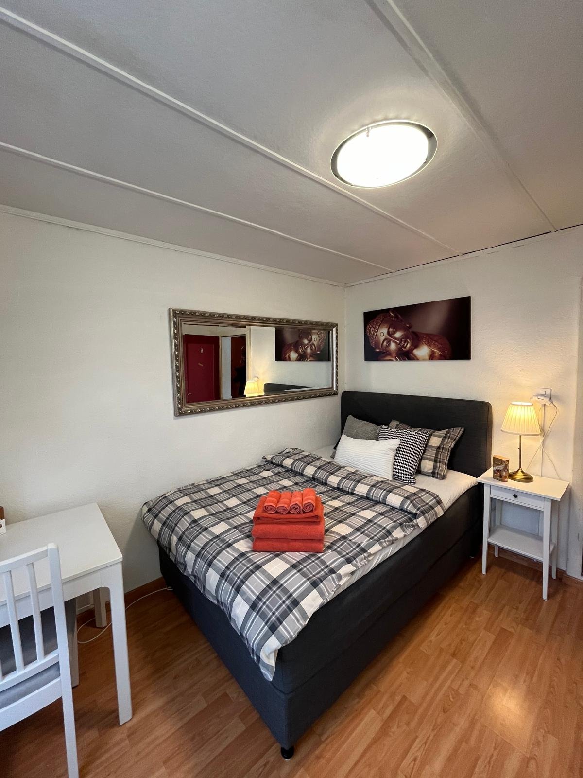 bedroom with bed, nightstand, lamp, mirror, and desk with chair