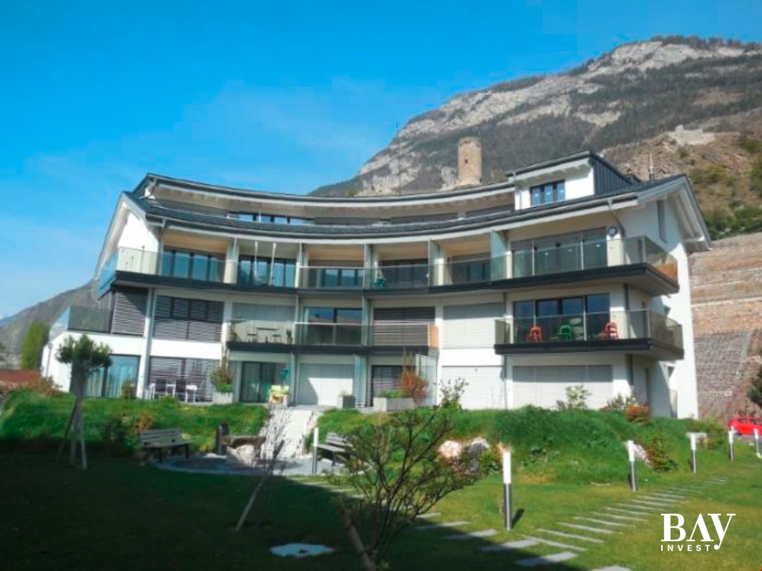 Large house with many windows, balcony on each floor, mountain view