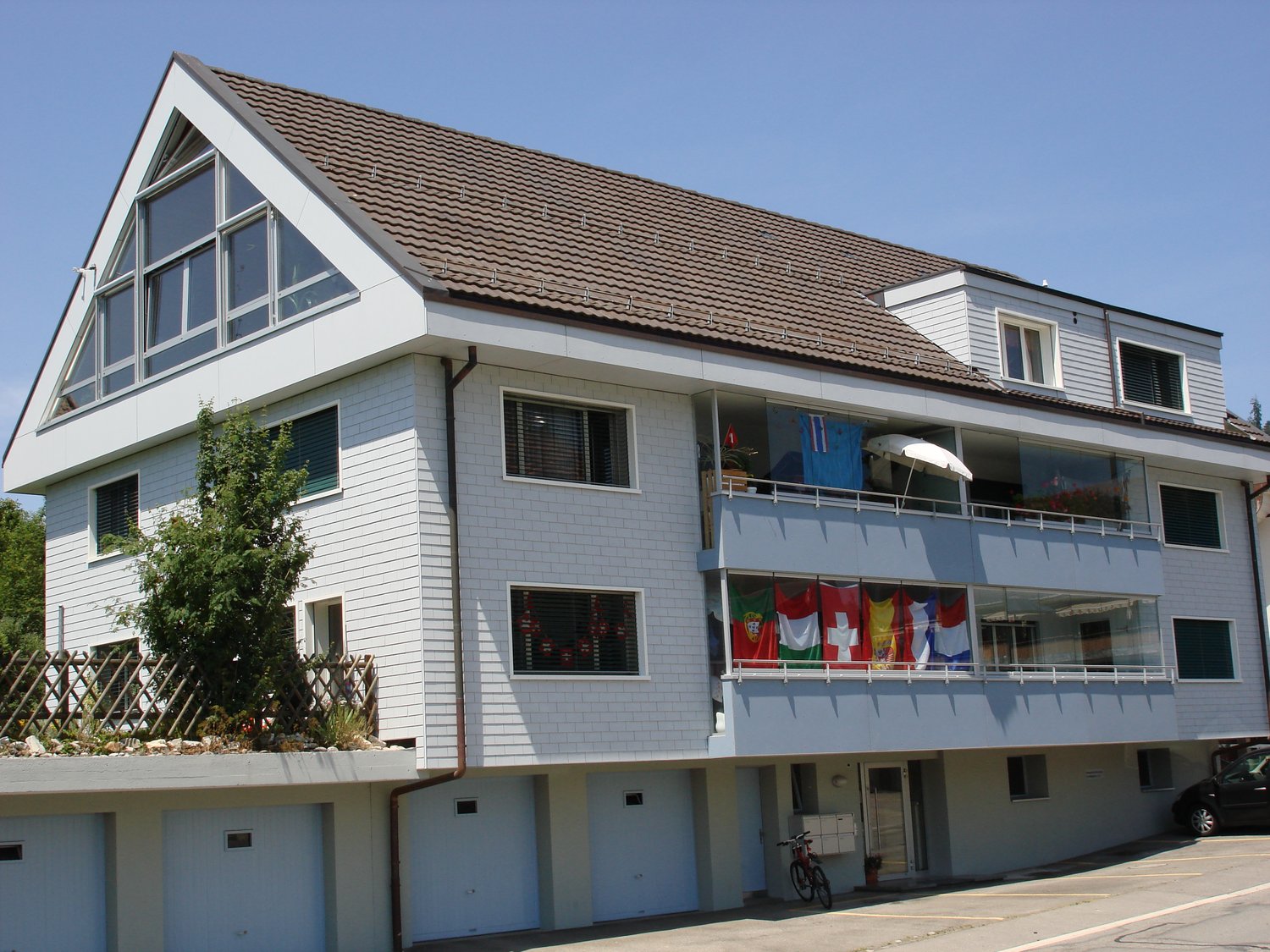 white house, 3 stories, multiple balconies, garage, parking
